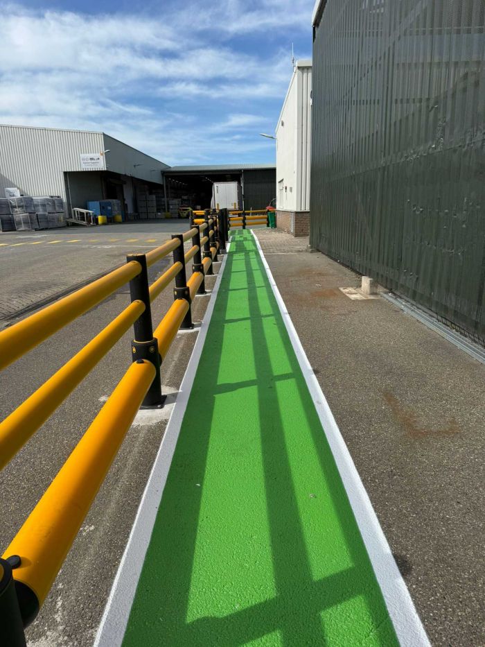Groen gemarkeerd looppad langs veiligheidsleuningen op bedrijventerrein